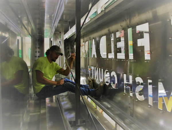 Sign fabricator works inside a metal sign.